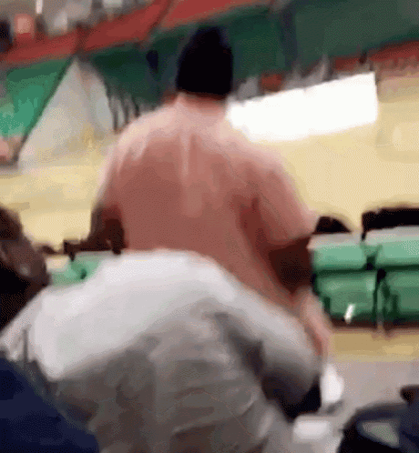 a man in a pink shirt is standing next to another man in a white shirt in a stadium .