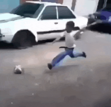 a young boy is running down a street in front of a car .