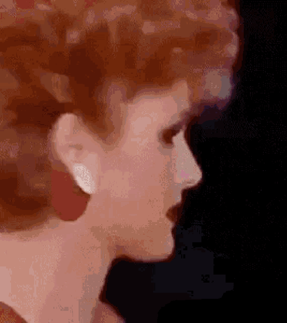 a close up of a woman 's face with red hair wearing red earrings .