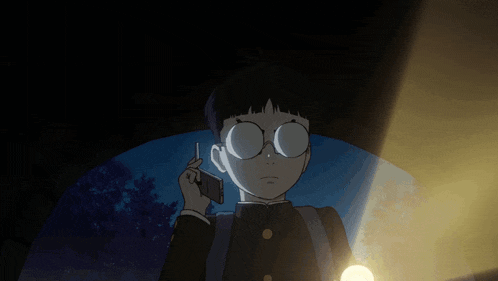 a boy with glasses talking on a cell phone in the dark