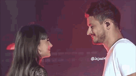 a man and a woman are looking into each other 's eyes while standing next to each other on a stage .
