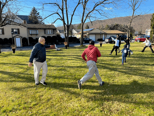 a group of people are playing a game in a grassy field with a man wearing a red hoodie with the number 7 on it