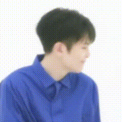 a young man in a blue shirt is sitting down and looking down .