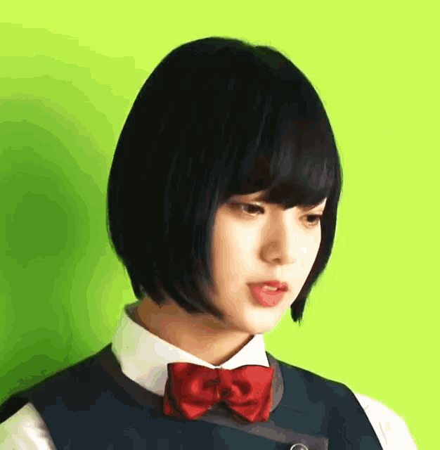 a girl wearing a blue vest and a red bow tie against a green background