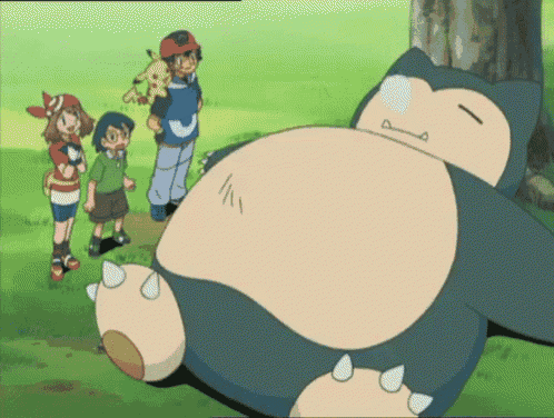 a group of kids standing around a sleeping snorlax in a field