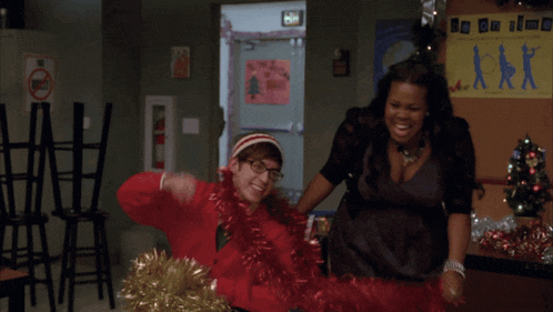 a man in a santa hat and a woman in a black dress are playing with red tinsel