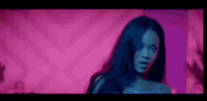 a woman in a blue dress is standing in front of a pink wall .