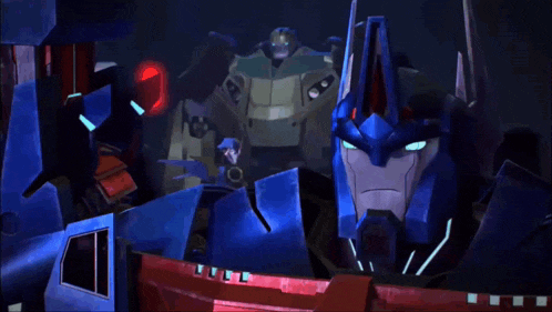 a group of transformers are looking at each other and one of them has a red light on his head