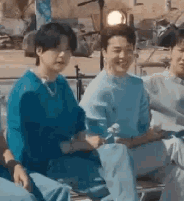 a group of people are sitting next to each other on a bench .
