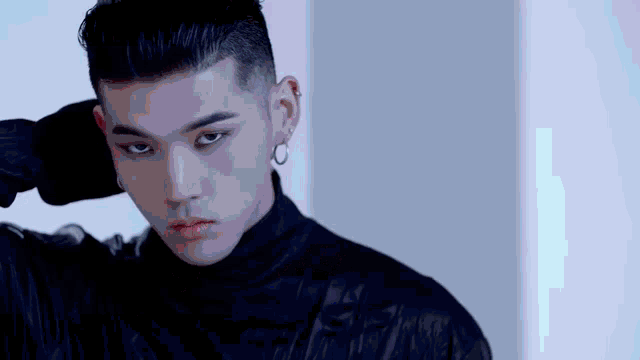a close up of a man wearing a black turtleneck and earrings .