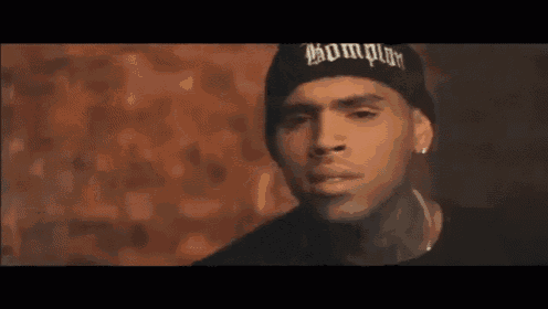 chris brown is wearing a black beanie and earrings .