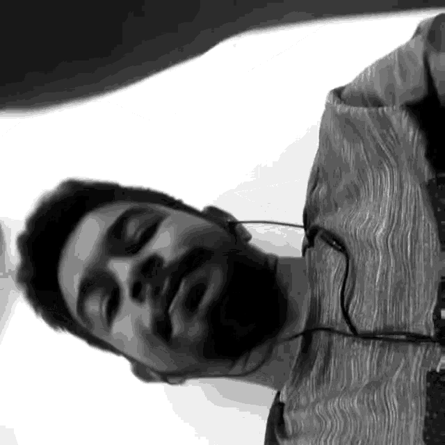 a man with a beard is wearing headphones and a gray shirt .