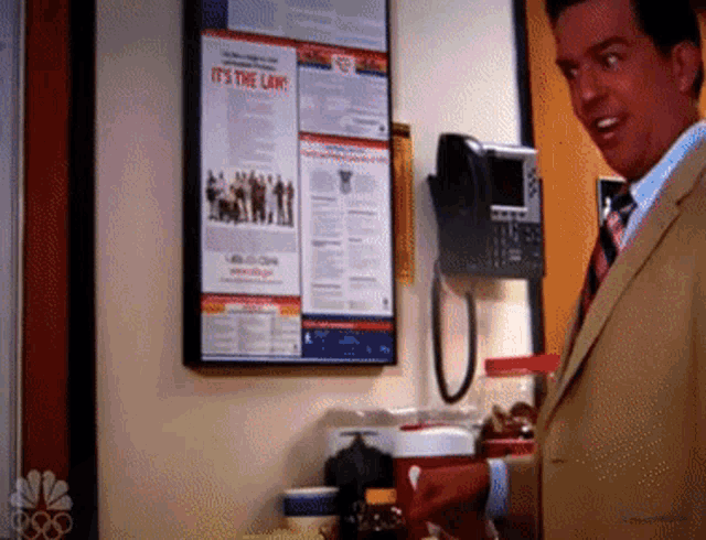 a man in a suit and tie is standing in front of a sign that says it 's the law