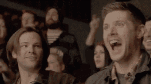 a group of people are sitting in a stadium watching a game and one man is screaming .