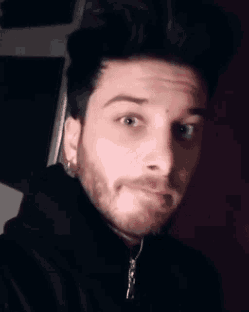a close up of a man with a beard making a funny face with his tongue out .