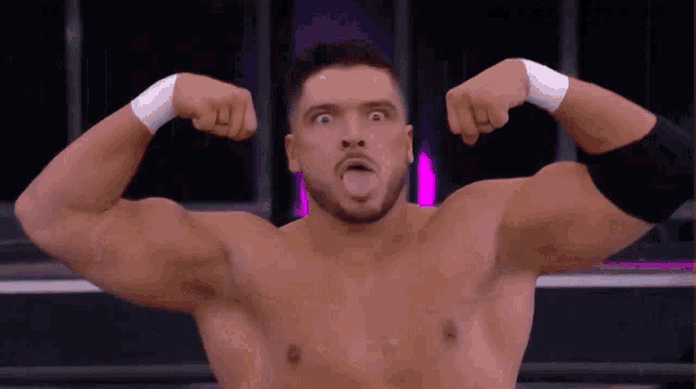 a wrestler without a shirt is flexing his muscles and sticking his tongue out