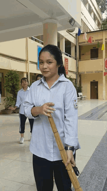 a girl is holding a broom in front of a building with a sign that says ' a ' on it