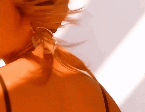 a close up of a woman 's neck and back with her hair blowing in the wind