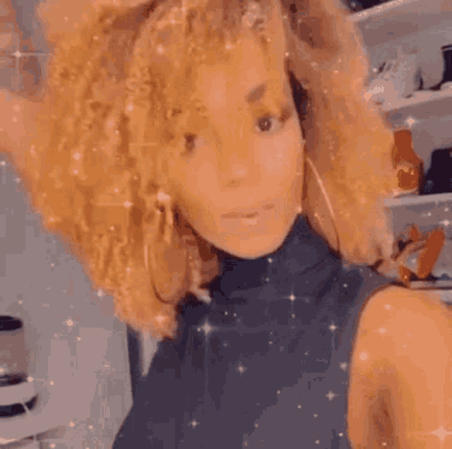 a woman with curly hair is giving a peace sign while wearing a black tank top .