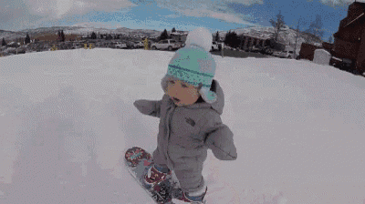 a little girl is standing on a snowboard wearing a hat