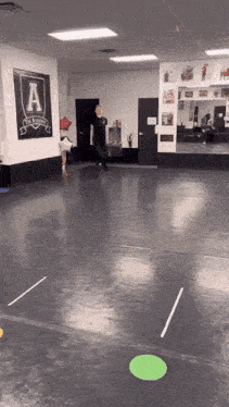 a man stands in a gym with a sign on the wall that says the academy