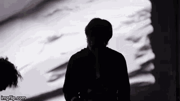 a silhouette of a man standing in front of a projection of a woman 's face .