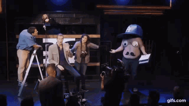 a man wearing a la hat with big eyes and a mustache is standing next to a woman .