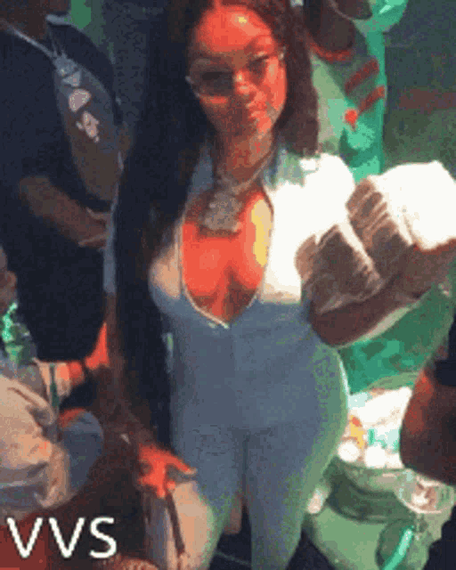 a woman in a white jumpsuit is holding a stack of money in her hand