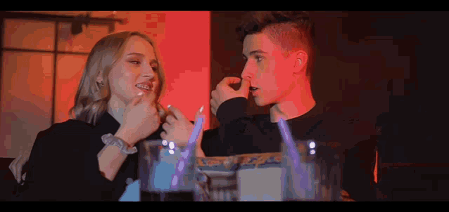 a man and a woman are looking at each other in a dark room .