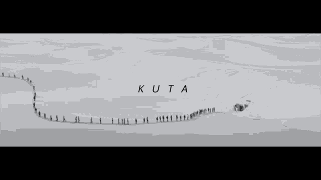a group of people are walking through a snowy field and the word kuta is on the bottom right