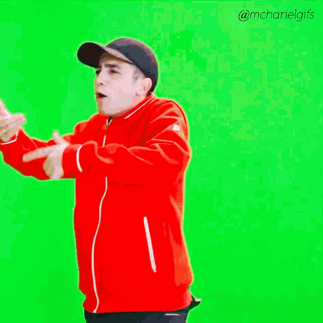 a man in a red jacket and black hat is dancing on a green screen ..