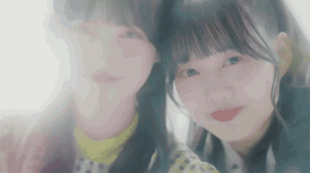 a couple of girls standing next to each other and looking at the camera