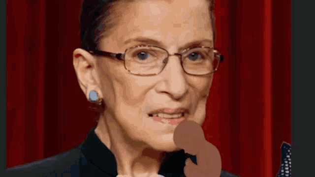 a close up of a woman wearing glasses and a black suit