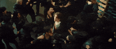 a group of people are gathered around a man in a black jacket