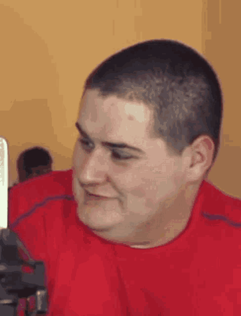 a man in a red shirt is making a funny face in front of a camera .