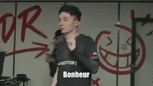 a young man is standing in front of a wall with the words `` c'est que du bonheur '' painted on it .