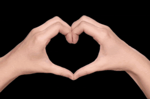 a person is making a heart shape with their hands in front of a fireball