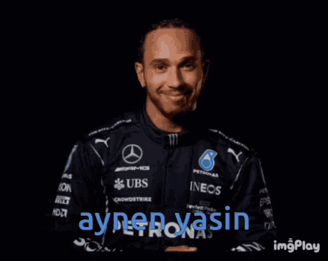 a man wearing a mercedes shirt is smiling and giving a thumbs up sign