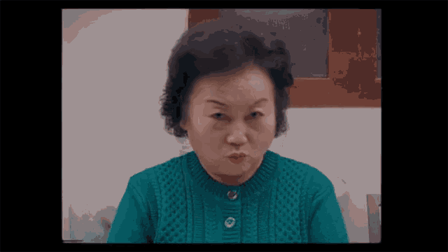 a woman in a green sweater with buttons on the front is making a funny face
