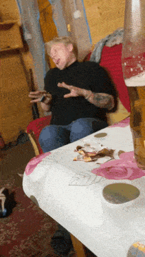 a man sitting on a couch next to a table with a coca cola glass on it