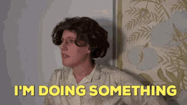 a woman wearing glasses and a wig is saying i 'm doing something .