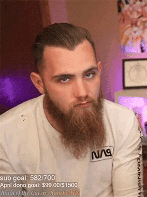 a man with a beard wearing a nasa shirt looks at the camera