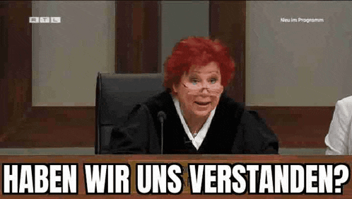 a woman with red hair is sitting at a desk with the words haben wir uns verstanden written on it