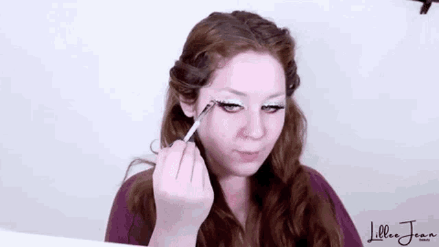 a woman is applying makeup to her face with a brush in front of a mirror .