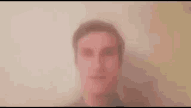a blurry picture of a man 's face behind a white wall .