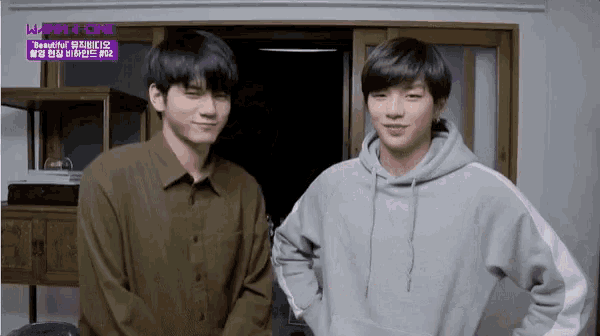 two young men are standing next to each other in front of a purple sign that says ' beautiful ' on it