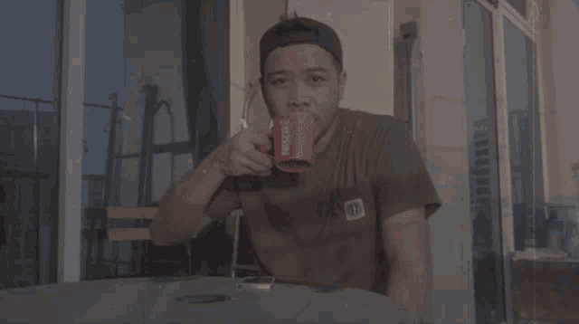 a man is drinking from a red nescafe cup