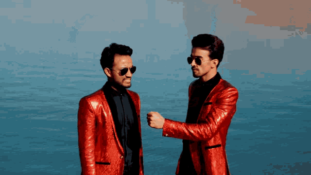 two men wearing red suits and sunglasses stand next to each other