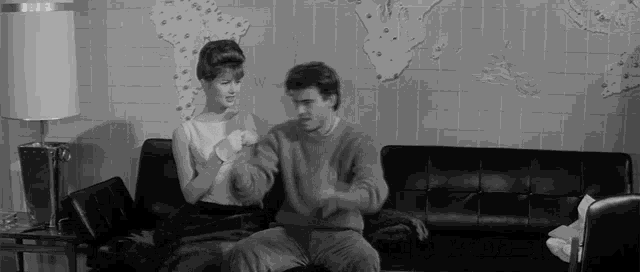 a man and a woman are sitting on a couch talking to each other .