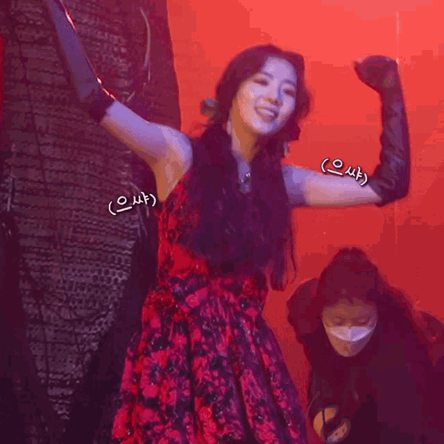 a woman in a red dress and black gloves stands in a dark room